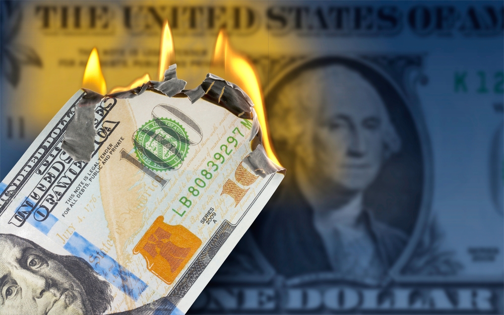 A burning 100 US dollar bill in front of One Dollar banknote 