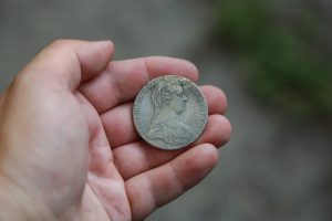 A hand holding a silver coin from Austria